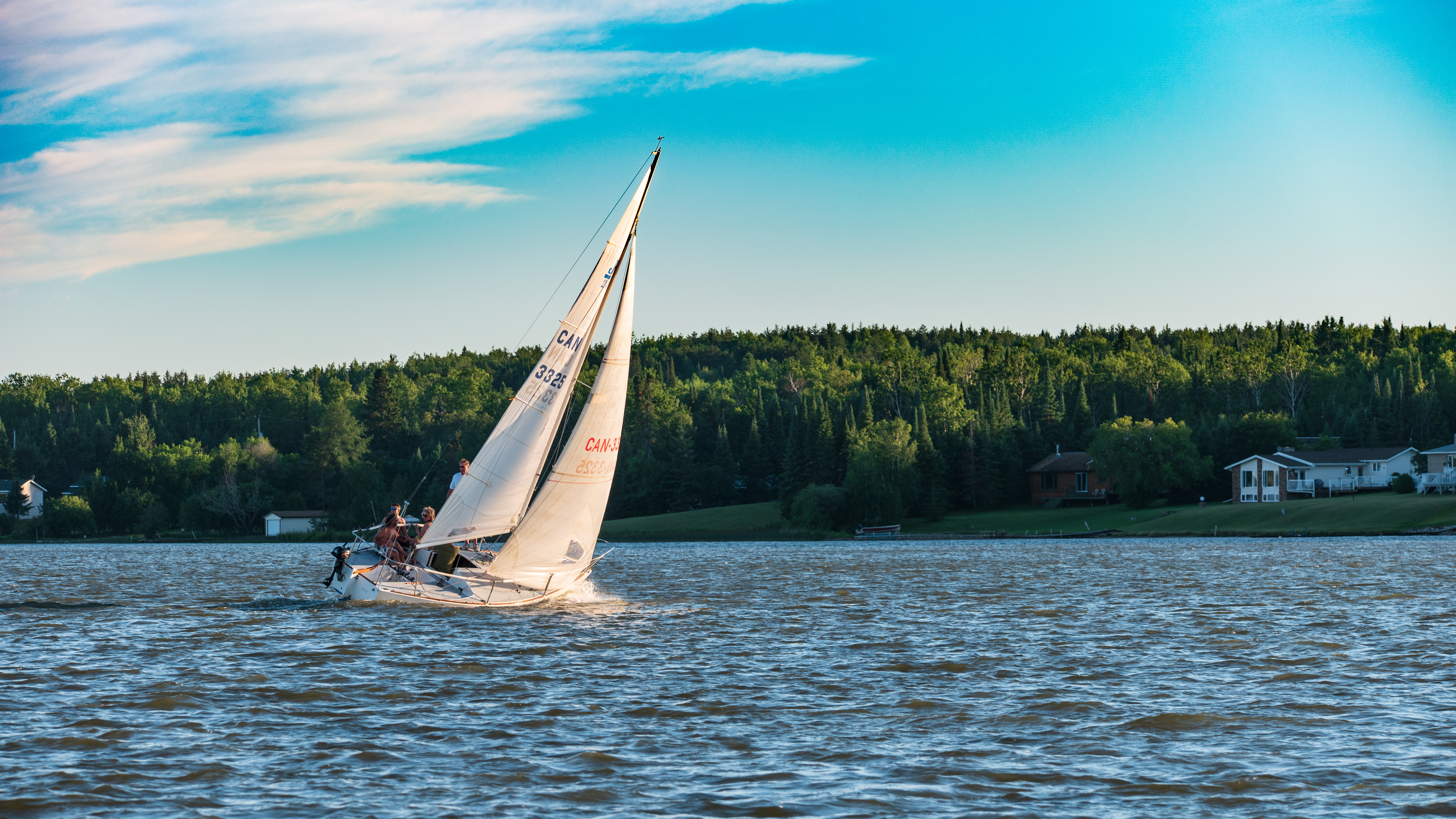 Sailboat gliding across a lake under a bright blue sky